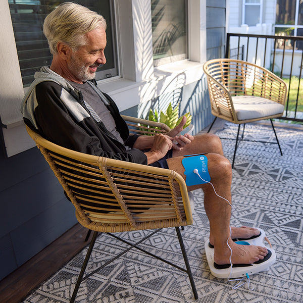 Image of a man using the Fllow device with the Arthro-Fllow pads on a chair on his porch