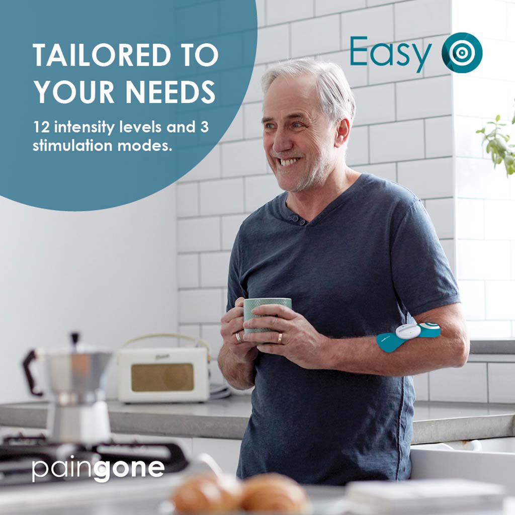 Man wearing the Paingone Easy device on the arm while smiling and holding a cup with the "Tailored to your needs. 12 intensity levels and 3 stimulation modes" message