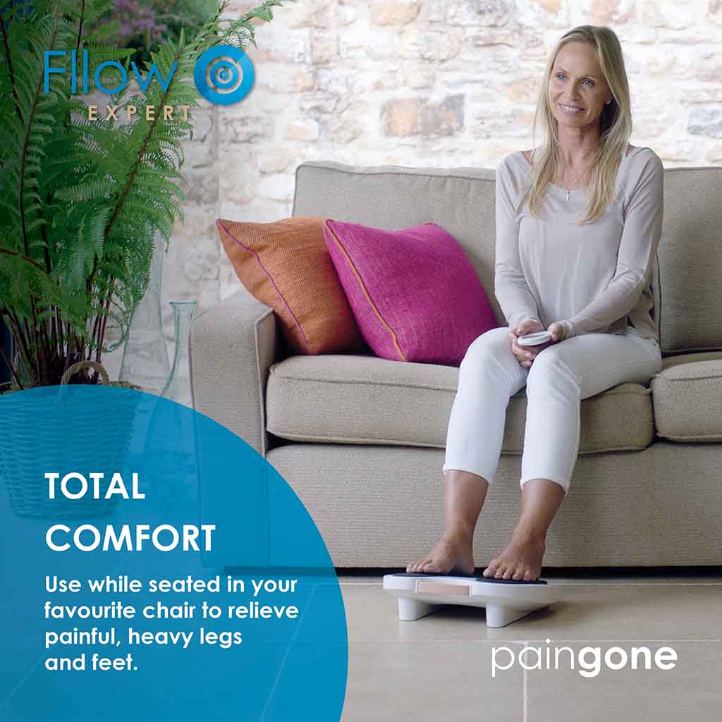 Image of a woman using the Paingone Fllow Expert device while on the couch with the message "Use while seated in your favourite chair to relieve painful, heavy legs and feet."