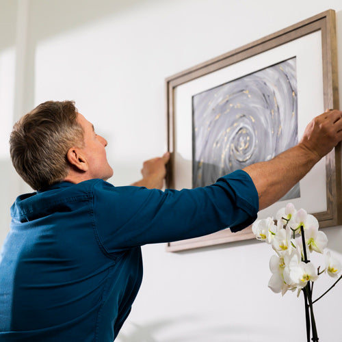 Image of a man hanging a painting